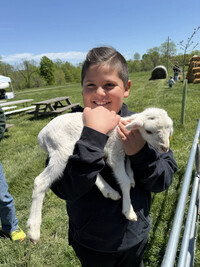  Ezra Cisneros holds a baby lamb at a local farm open house. Photo Credit: Bonnie Jean Feldkamp 