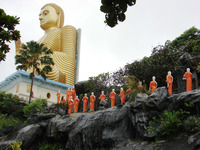 Monk statues bearing alms head toward the giant golden Buddha at Dambulla in Sri Lanka. Photo courtesy of Sandra Scott.