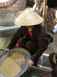 A participant in a "being like a farmer" experience in Thuy Bieu, Vietnam, learns to sift rice. Photo courtesy of Kitty Morse.