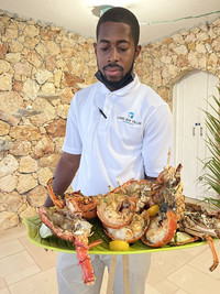 A butler delivers a seafood dinner to guests at Long Bay Villas on the Caribbean island of Anguilla. Photo courtesy of Candyce H. Stapen.