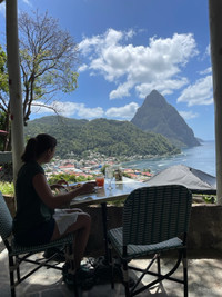 . A guest enjoys open-air dining on local Creole cuisine at the Green Fig Resort with Petit Piton in the distance beyond Soufriere, St. Lucia. Photo courtesy of Lesley Frederikson. 