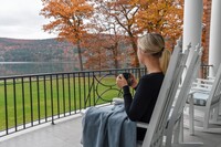 A visitor enjoys the verandah at the historic Otesaga Resort Hotel in Cooperstown, New York. Photo courtesy of the Otesaga Resort Hotel.