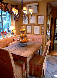  Banquette seating and a wall of chef-autographed menus cozy up a kitchen cubby reclaimed for dining. Photo courtesy of Leo Sorel. 