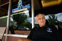 Gregory Ionadi, 75, sits in front of Smoke N' Guns, which he owns with his son, Gregory 'Gooch' Ionadi. Photo credit Justin Merriman